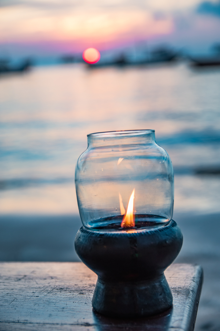 Close-up of a jar with a flame by the water.