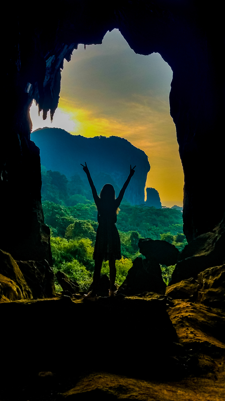 Silhouette of a person standing in a cave entrance with victory pose.