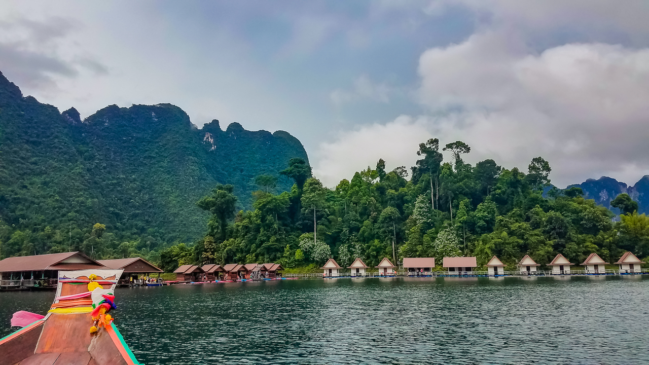 Floating bungalows on a lake surrounded by lush hills.