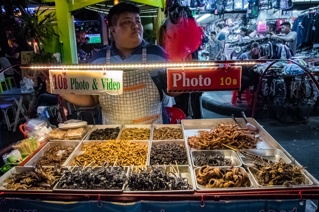 Street vendor selling fried insects at a night market.