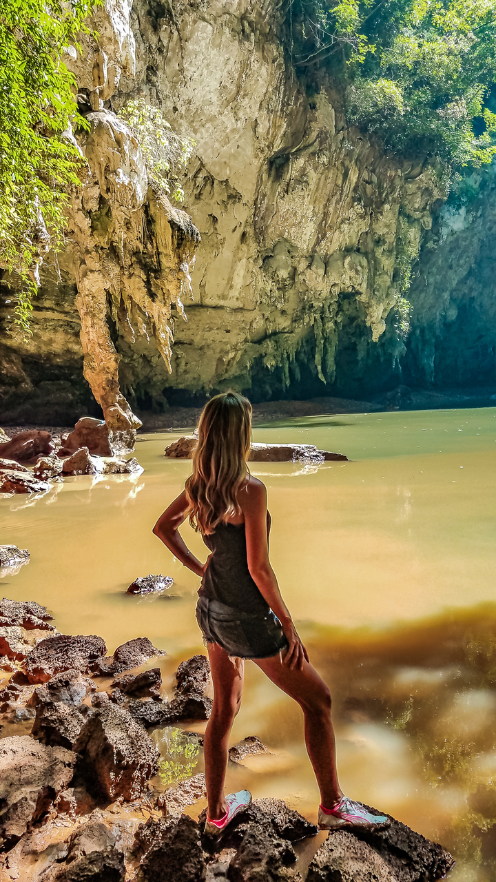 Person viewing a cave with water and rock formations.