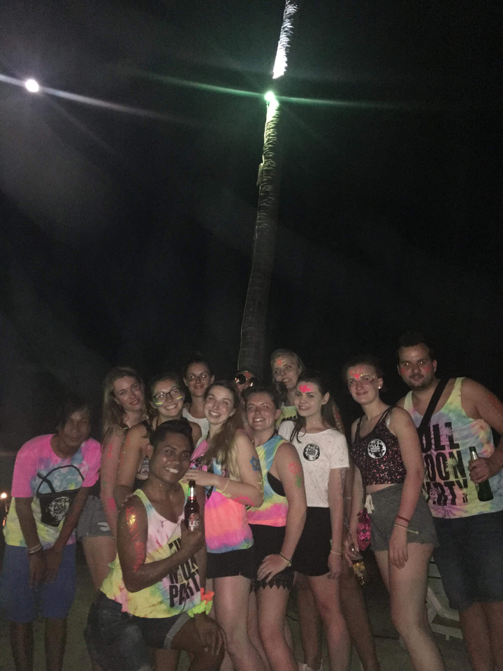 Group of people in party attire with glow paint at night.