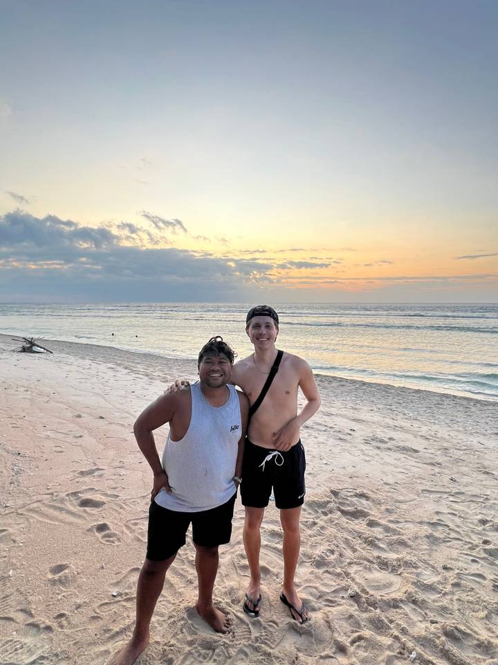 Two people posing on a beach during sunset.