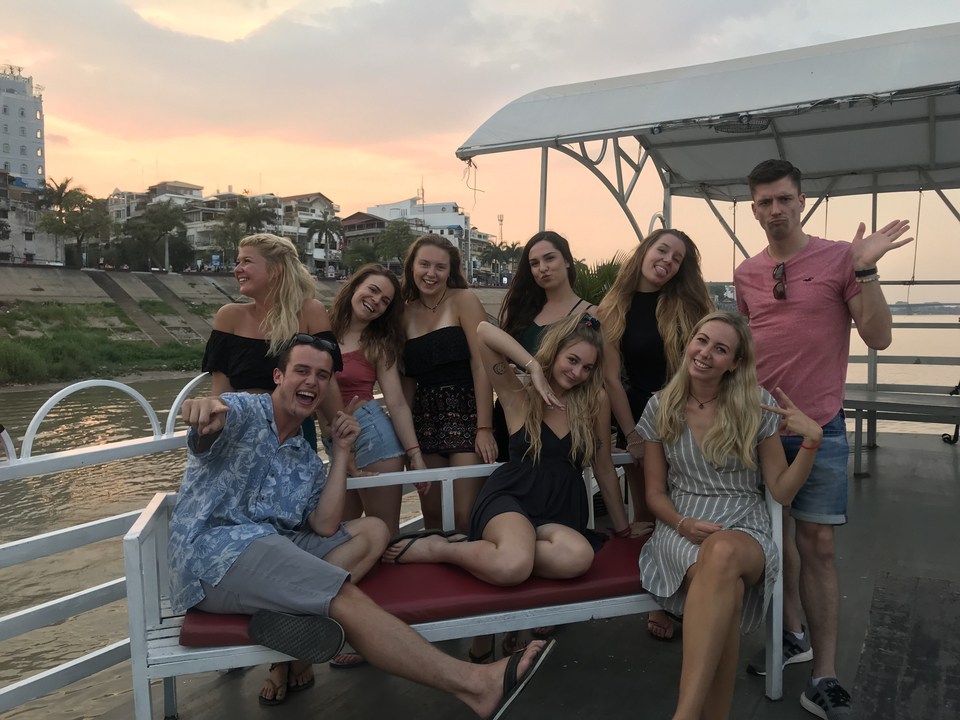 A group of young people posing on a boat with city views.