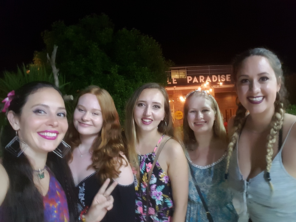 Un groupe de femmes souriant lors d'un événement nocturne en plein air.