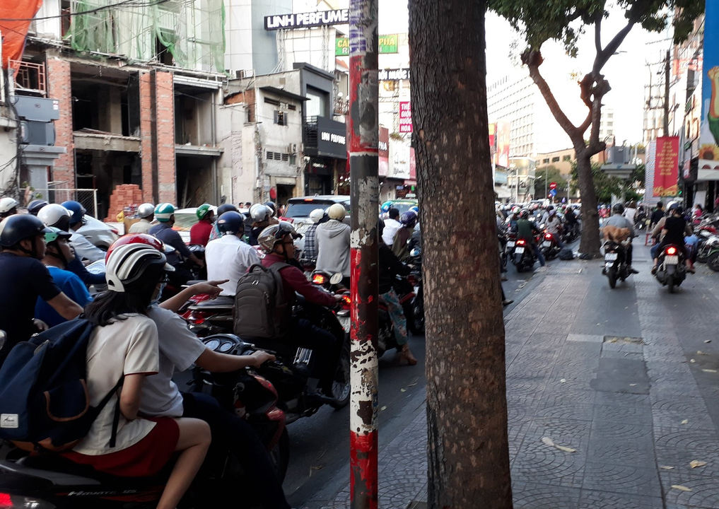 Rue de ville animée avec des motos et du trafic.