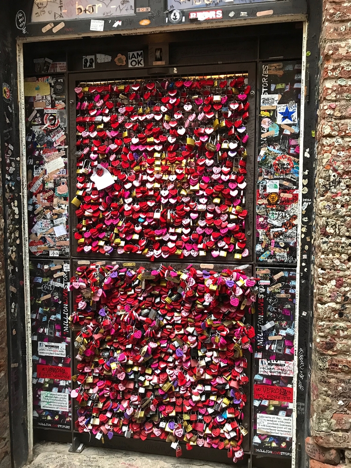 Wall covered with attached padlocks in various colors.