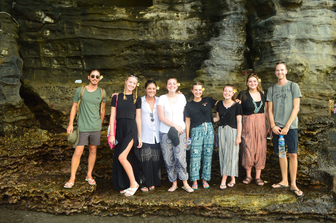 Group of tourists posing by rocky cliffs.