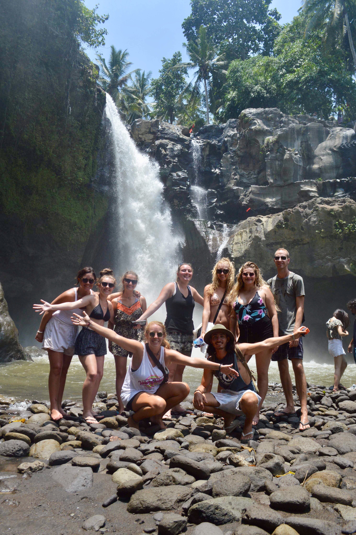 Tourists posing in front of a waterfall.