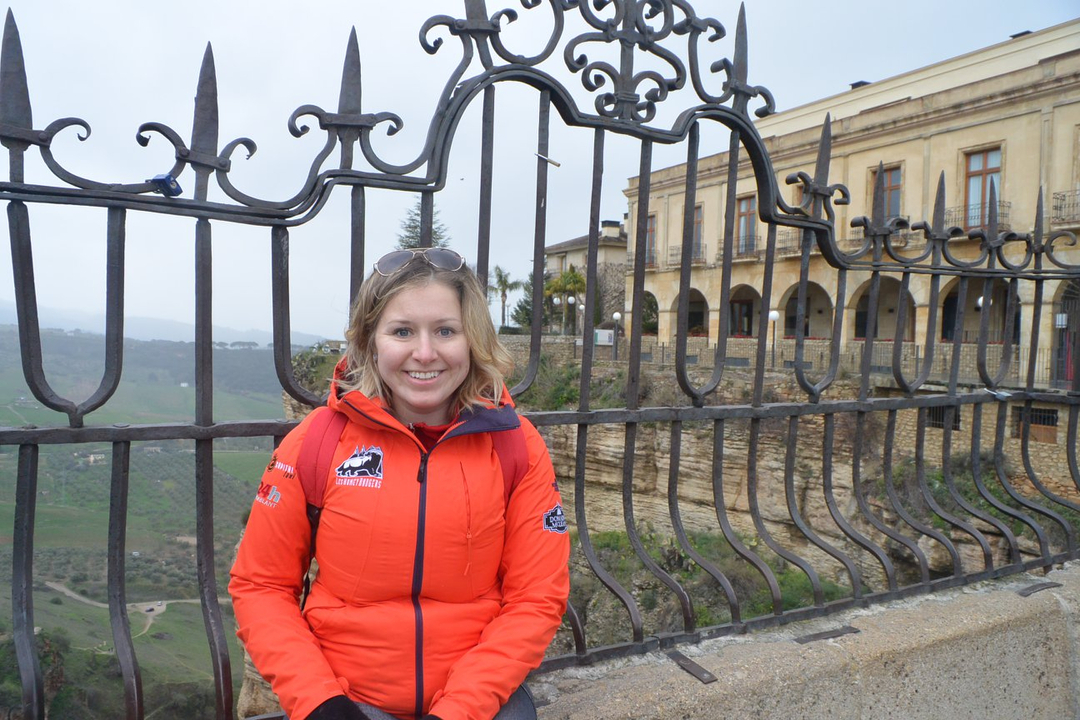 Personne assise près d'un bâtiment historique et d'une balustrade.
