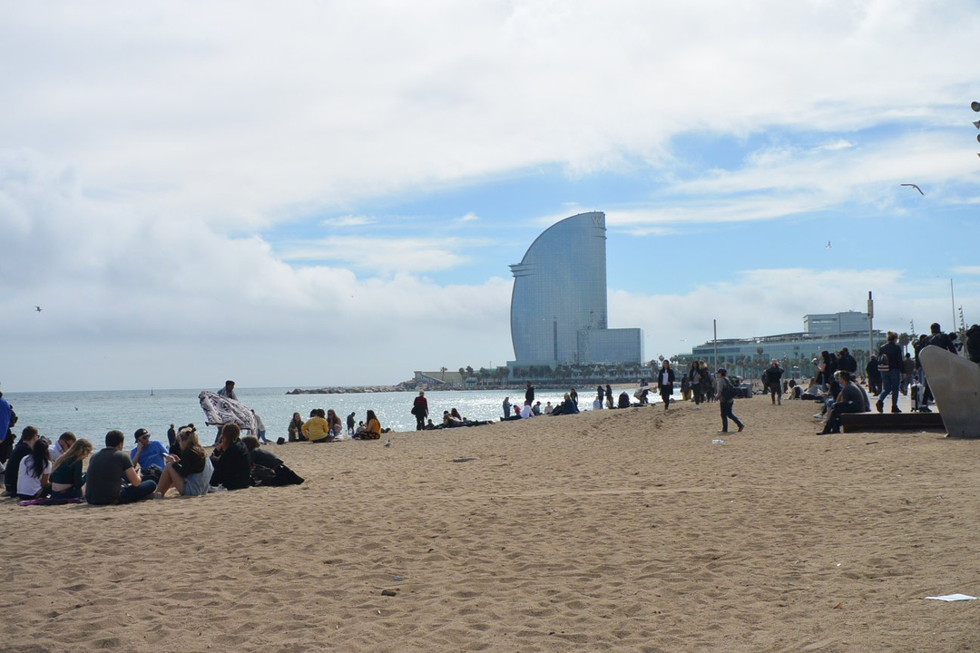 Des personnes profitant d'une journée à la plage avec un bâtiment futuriste en arrière-plan.