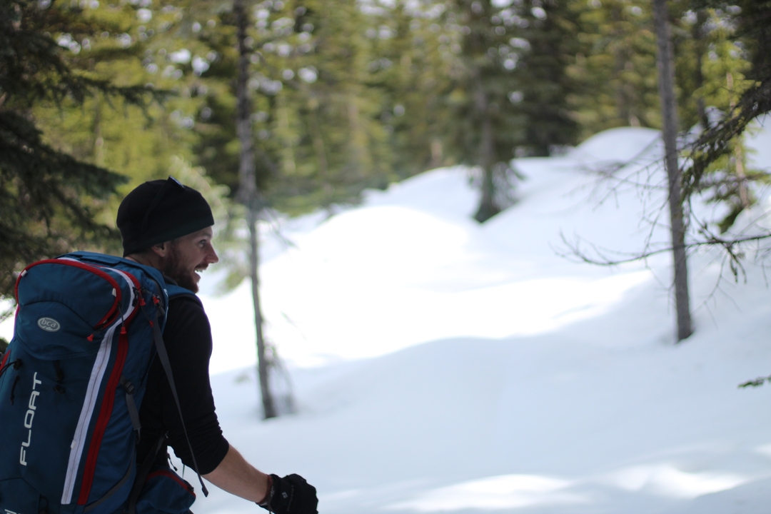 A person with a backpack walking through a snowy forest.