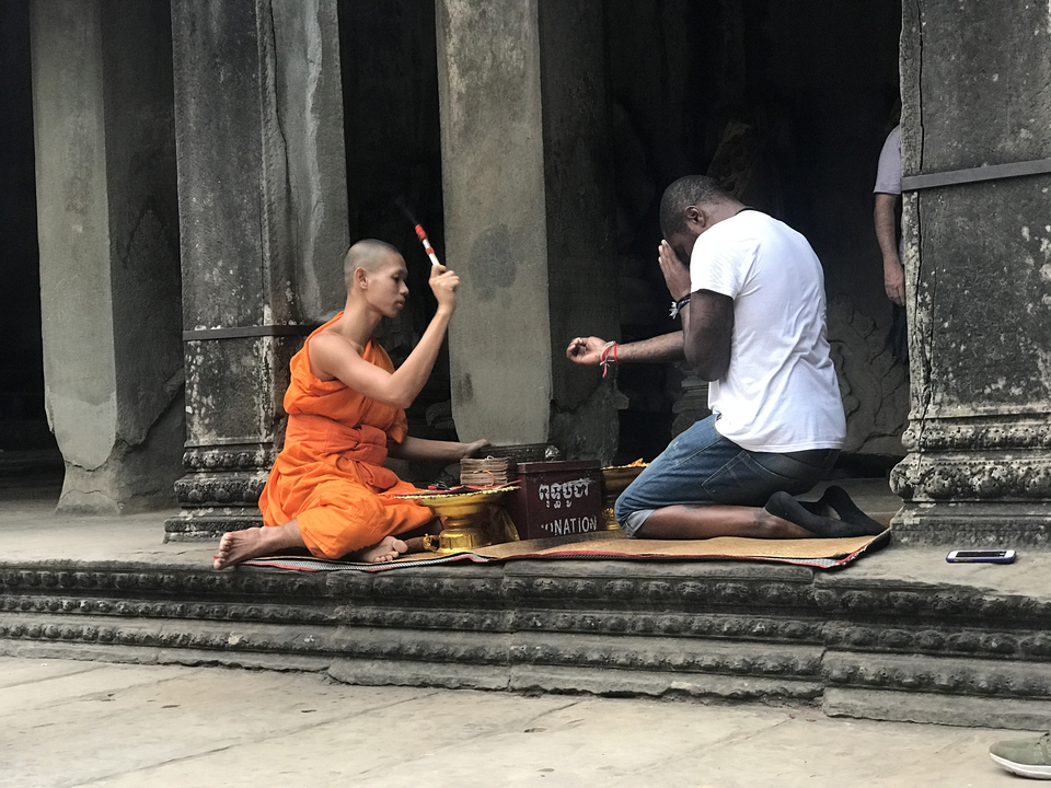 A monk performing a ritual with a person at a temple.