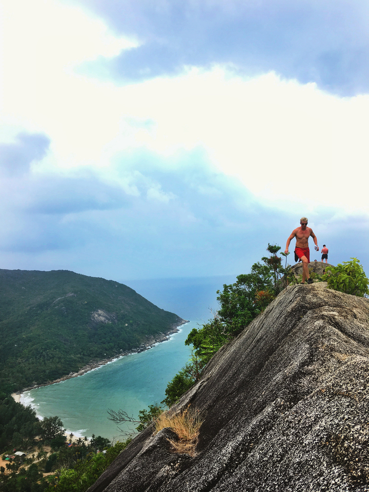 Person hiking on a rocky cliffside with an ocean view.