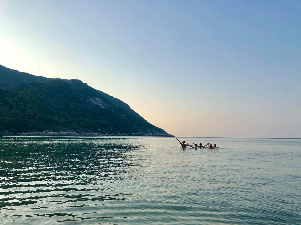 Personnes nageant dans l'océan au crépuscule.