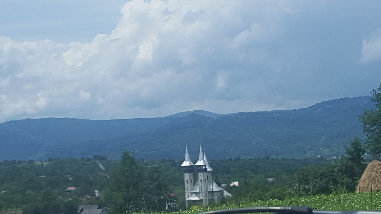 View of a white church with multiple spires in a rural landscape.