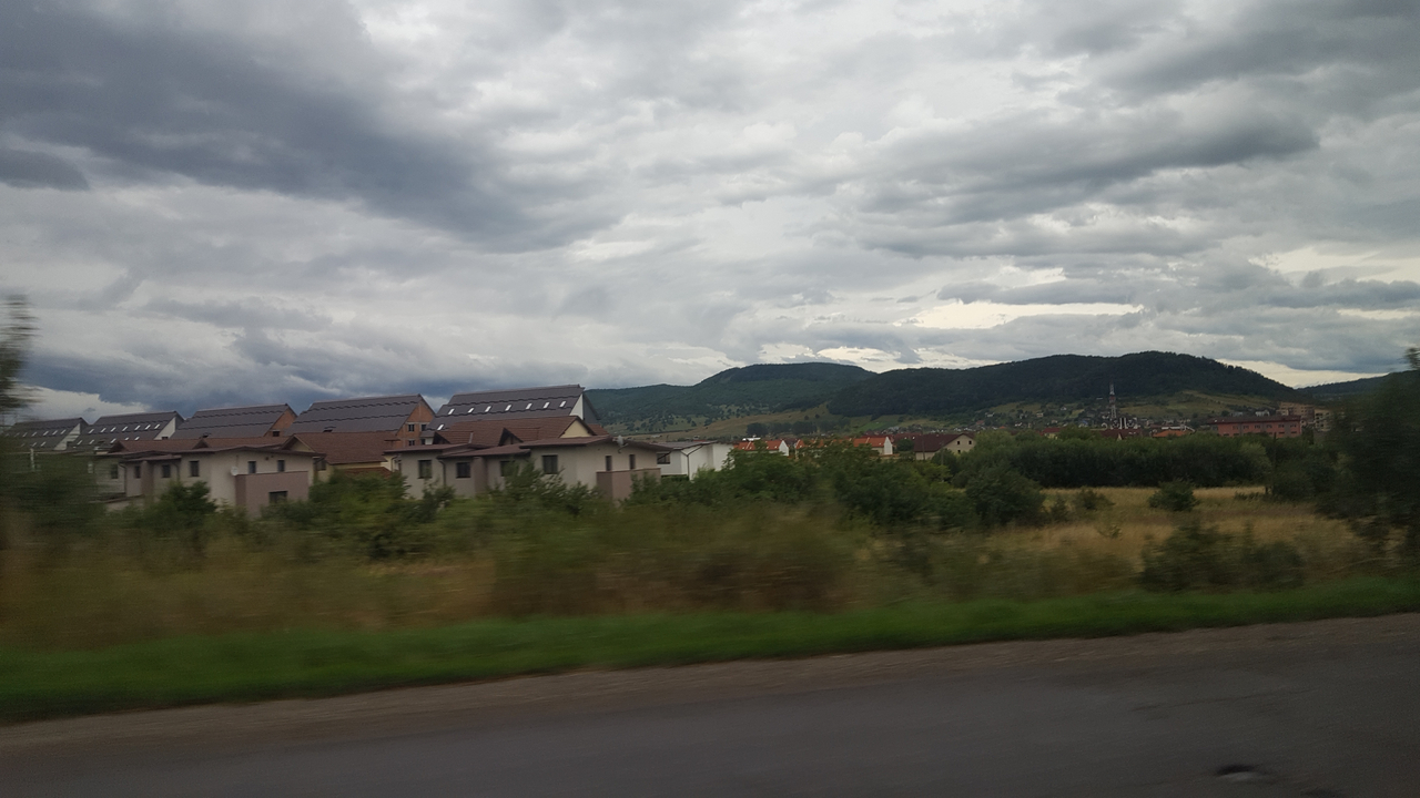Cloudy landscape with modern houses and fields.