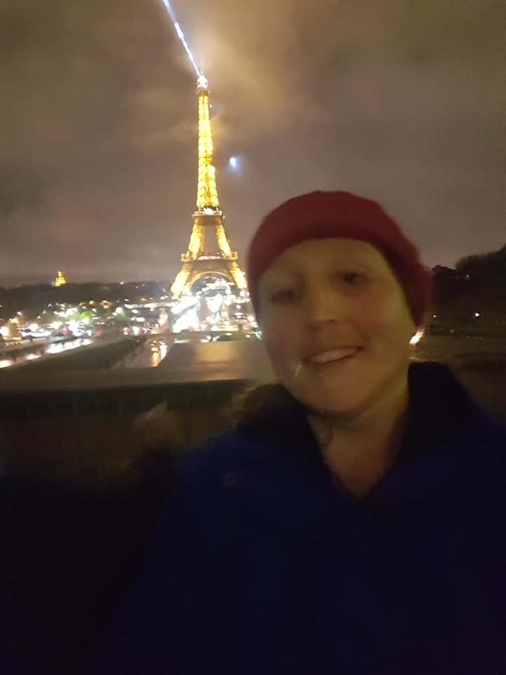 Blurry night shot of a person in front of a lit Eiffel Tower