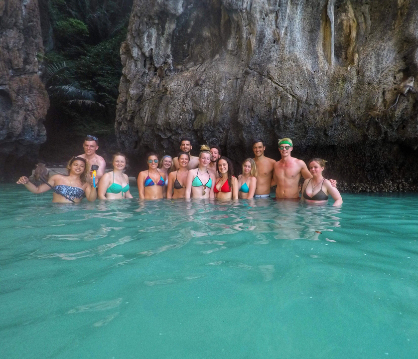 Group of people enjoying water near rock formations.