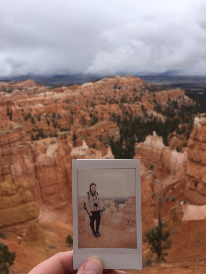 Hand holding a Polaroid against a canyon background.