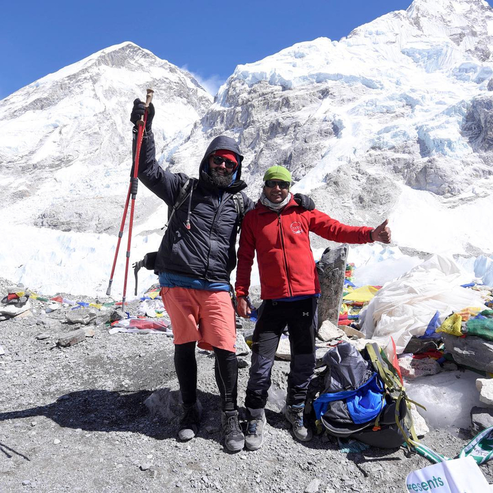 Deux personnes posant avec une vue de montagnes enneigées en arrière-plan.