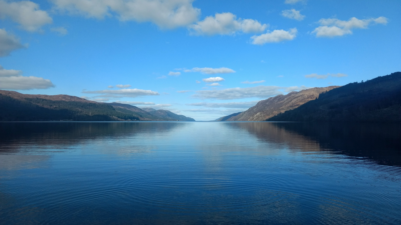 Calm lake reflecting the hills and clouds.