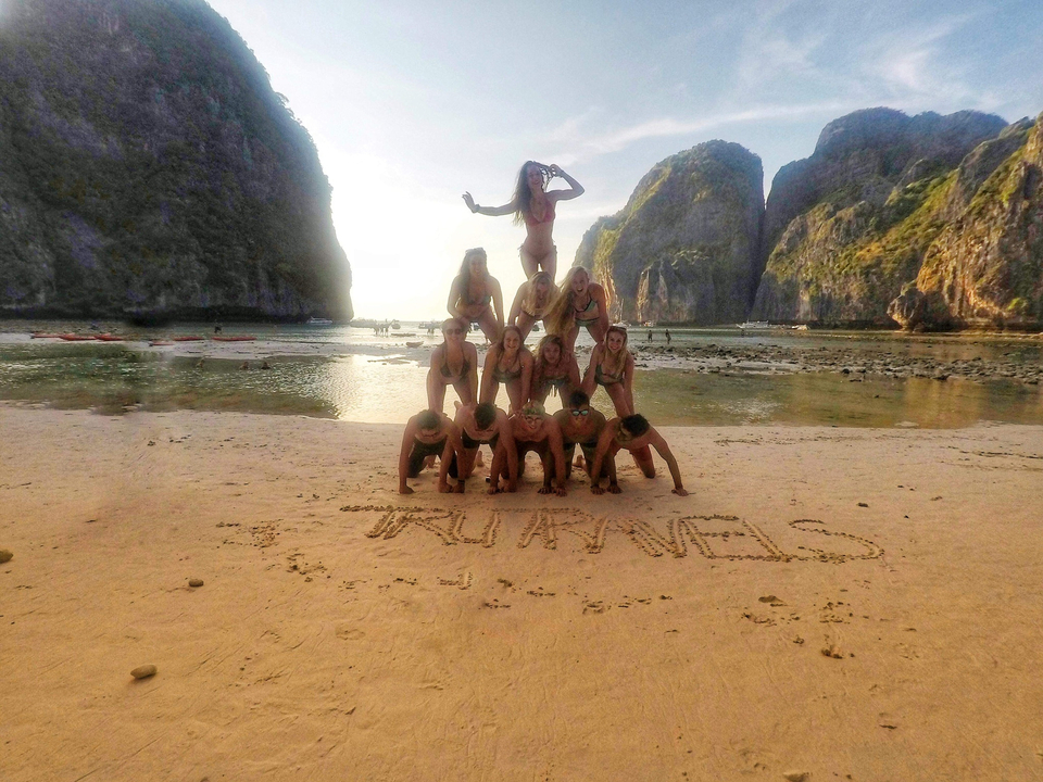People forming a human pyramid on the beach.