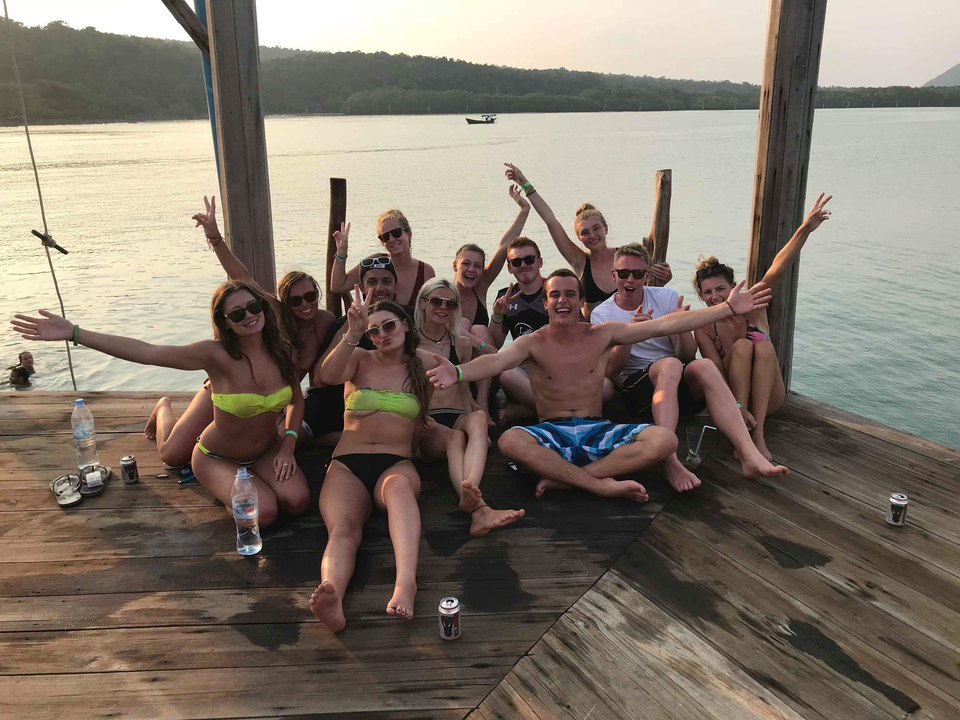 Group of friends posing on a pier with water in the background.