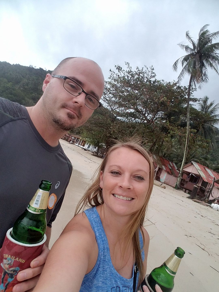 Two people on a beach with palm trees in the background.