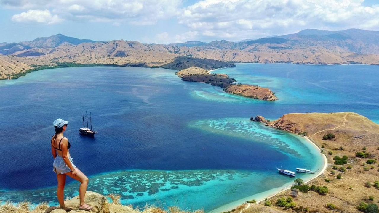 Person standing on a hill overlooking a tropical island bay.