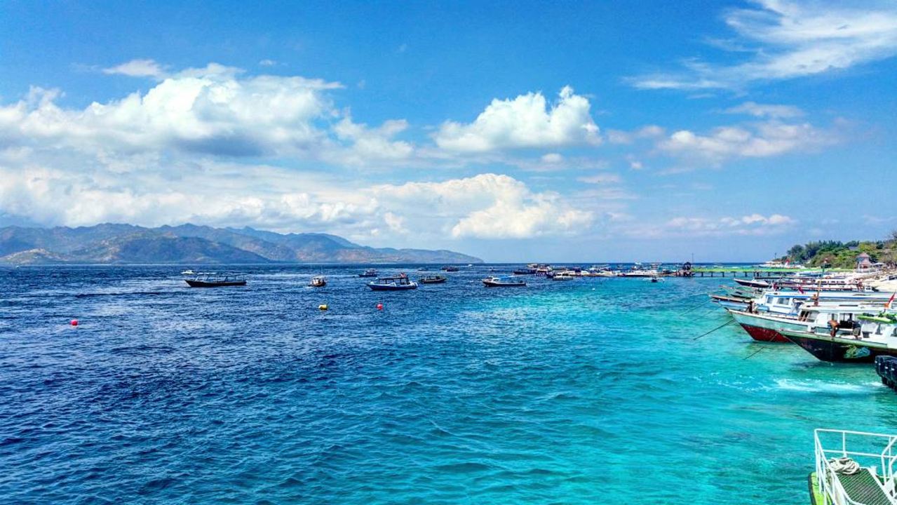 Turquoise waters with distant mountains and boats.