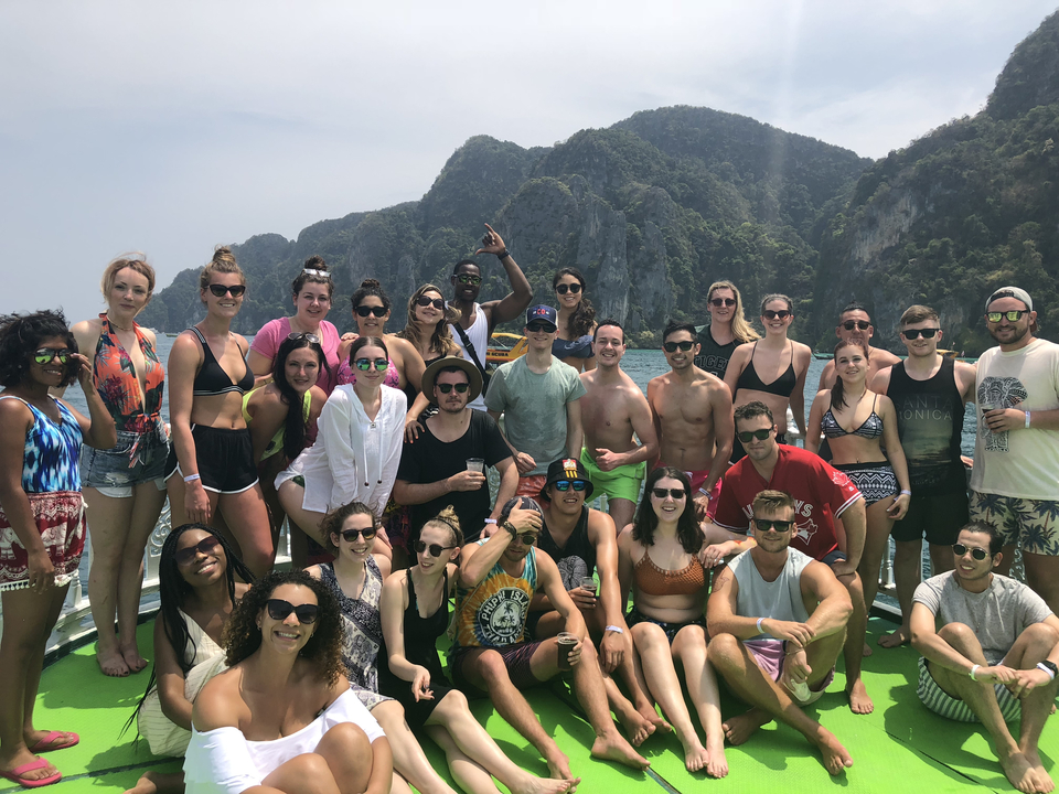 Large group of people on a boat with scenic mountains in the background.