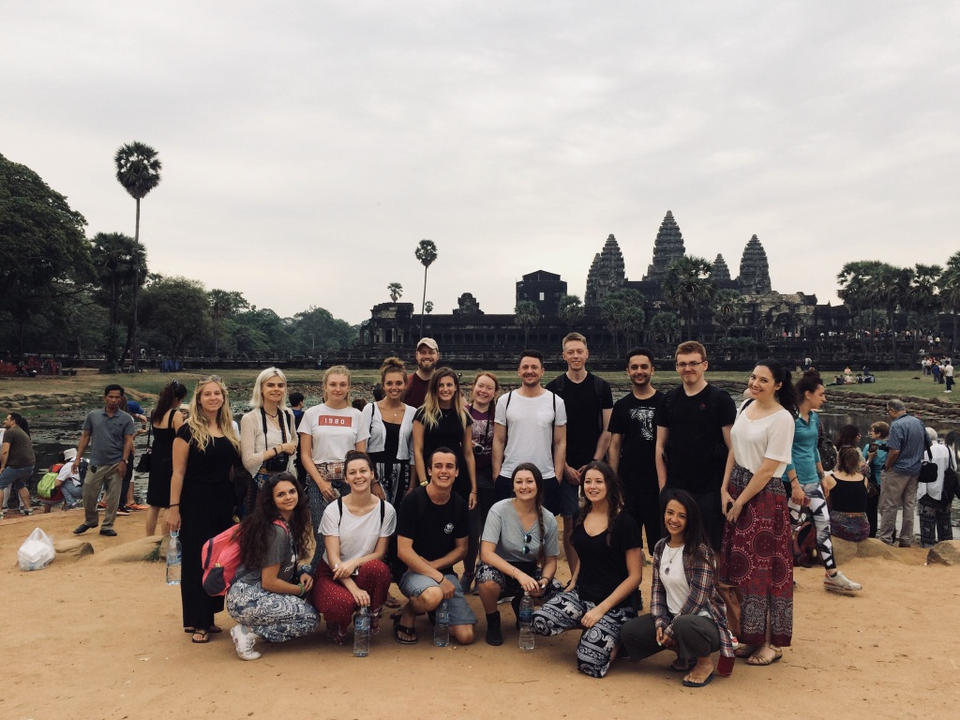 Group of tourists posing in front of Angkor Wat.