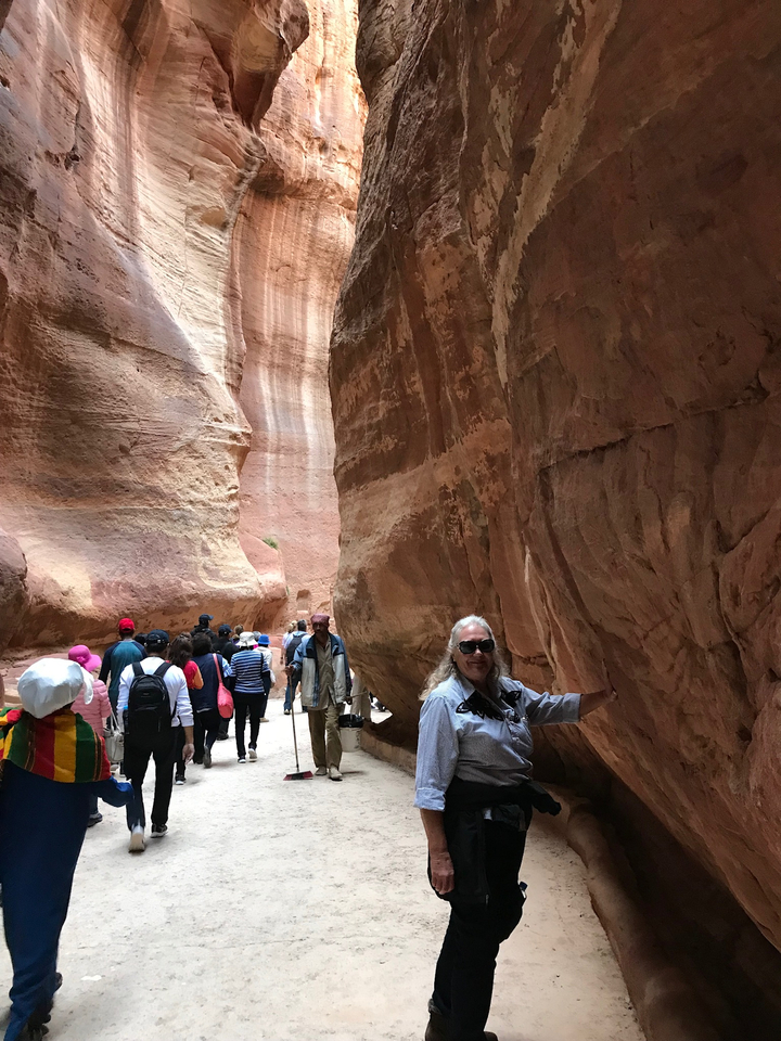 Visitors walking through a narrow rock canyon.