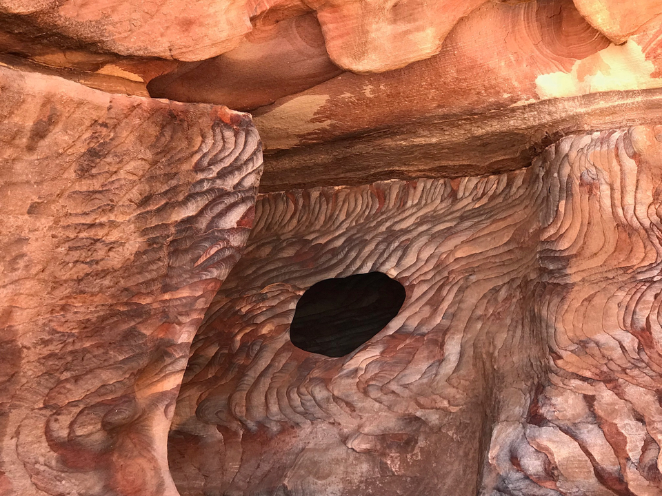 Rock walls with intricate natural patterns and a hole.