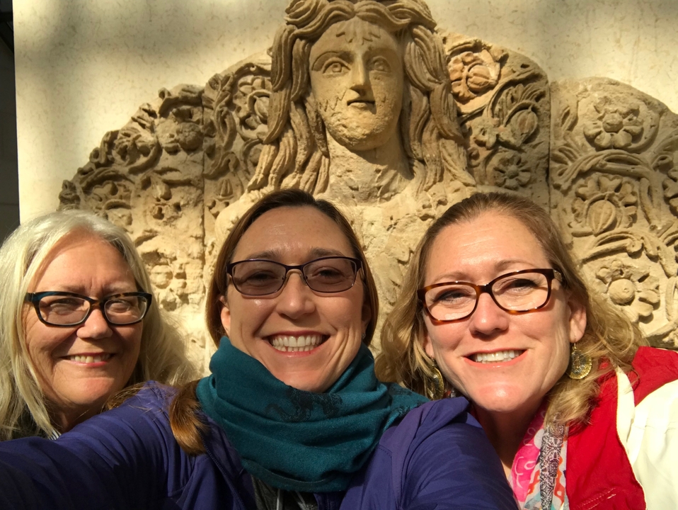 Group selfie in front of an ornate stone face carving.