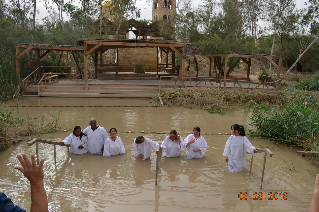 Des personnes en robe blanche se tenant debout dans l'eau boueuse.