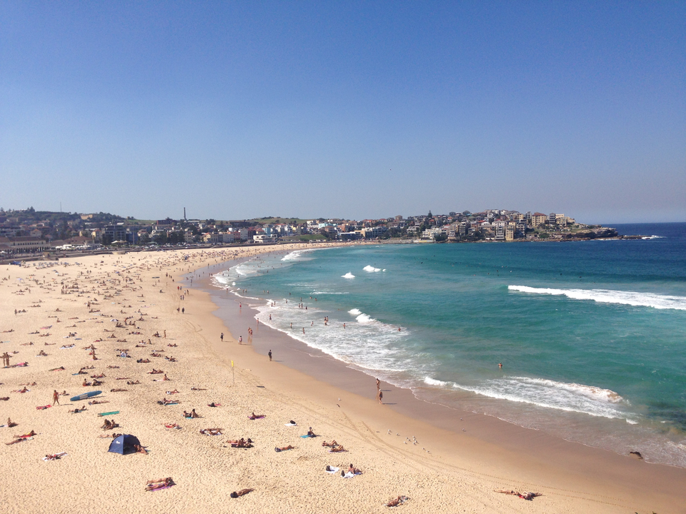 Aerial view of a sandy beach with clear blue water.
