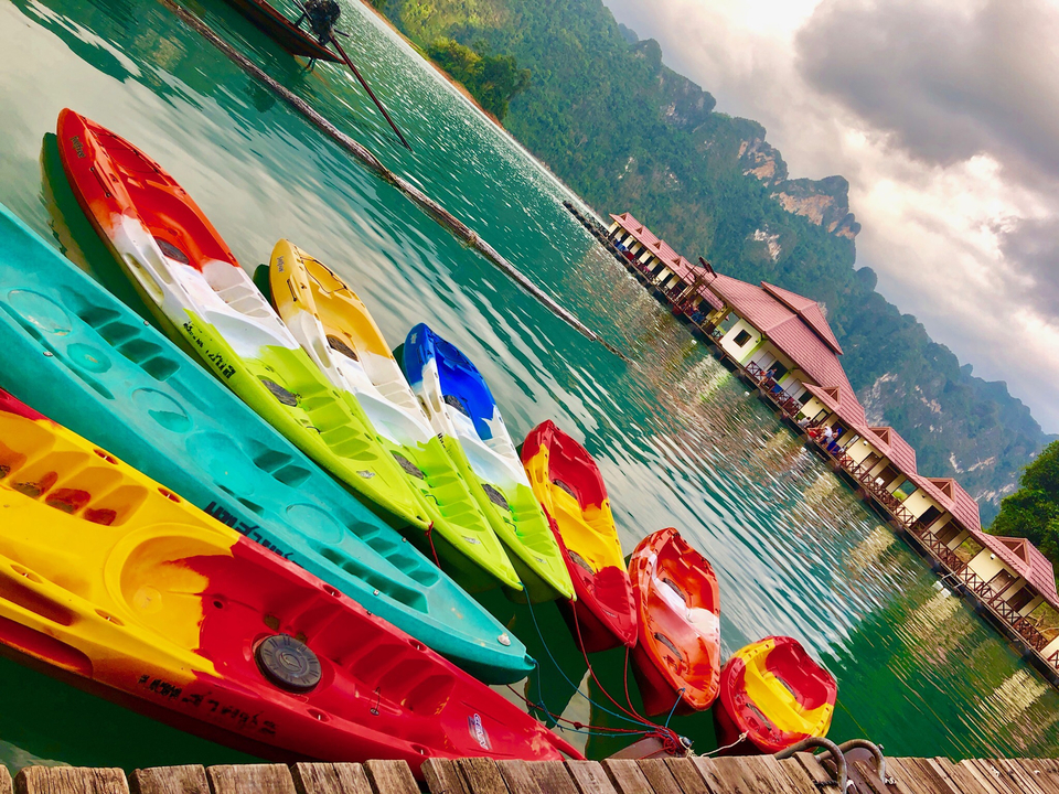 Colorful kayaks on a beautifully serene lake with hills in the background.