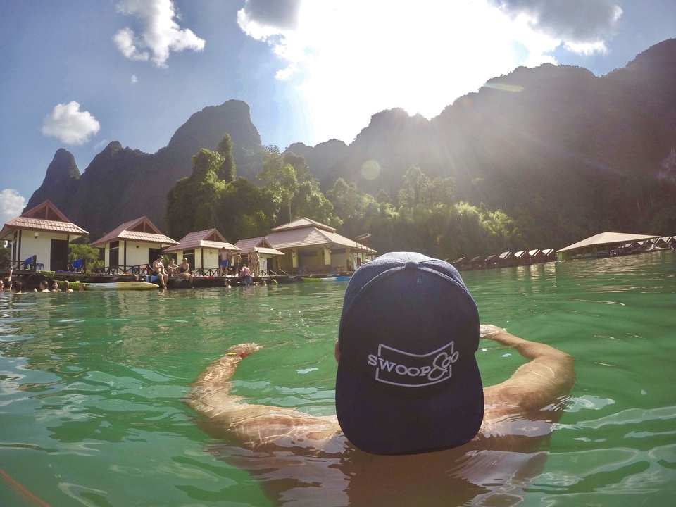 Person swimming in a lake close to floating bungalows.