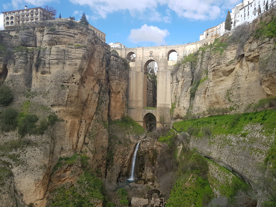A historic stone bridge over a gorge with a waterfall below