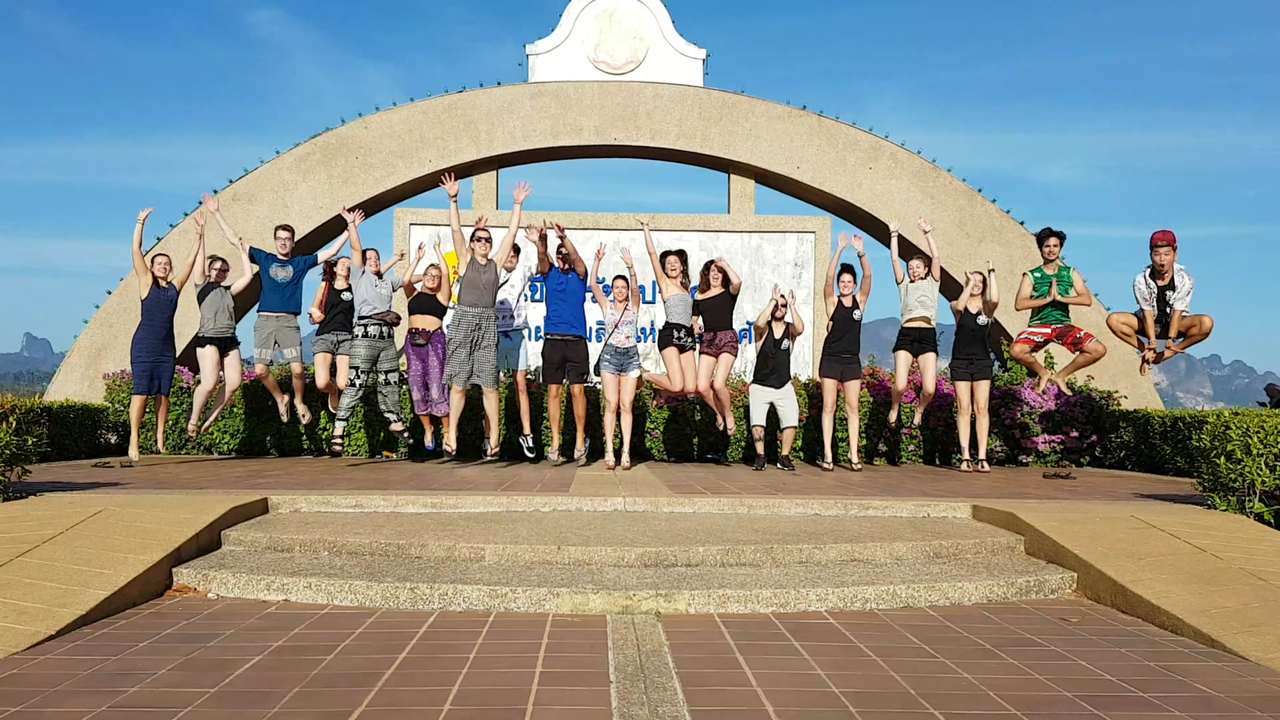 Group of people jumping in front of an arch with a landscape behind