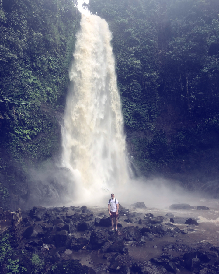 Person standing at the base of a waterfall