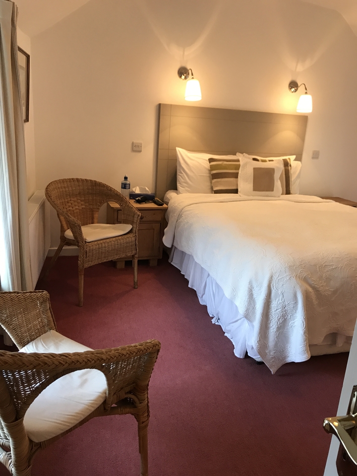 A cozy bedroom with a neatly made bed and a wicker chair.