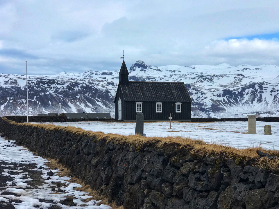 Black church with snow-capped mountains in the background.
