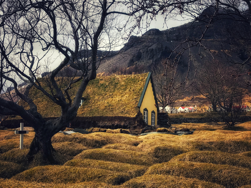Grass-roofed building with a mountainous backdrop.