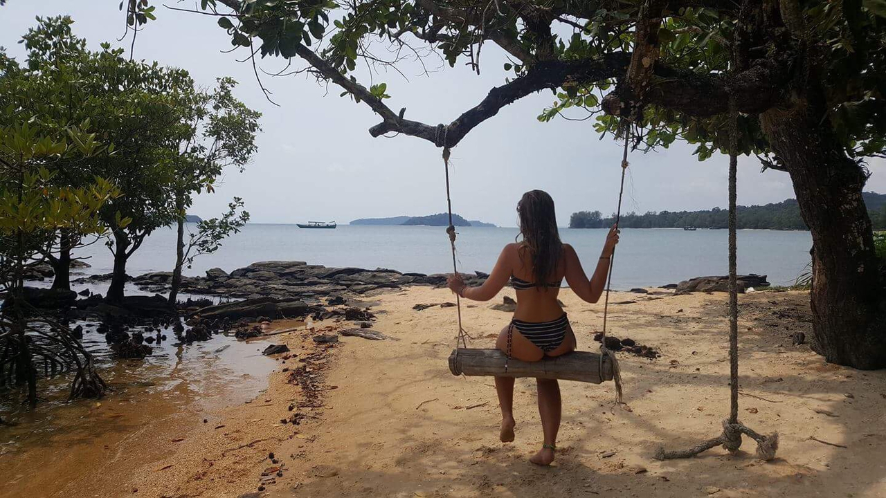 Person on a swing on a tropical beach.