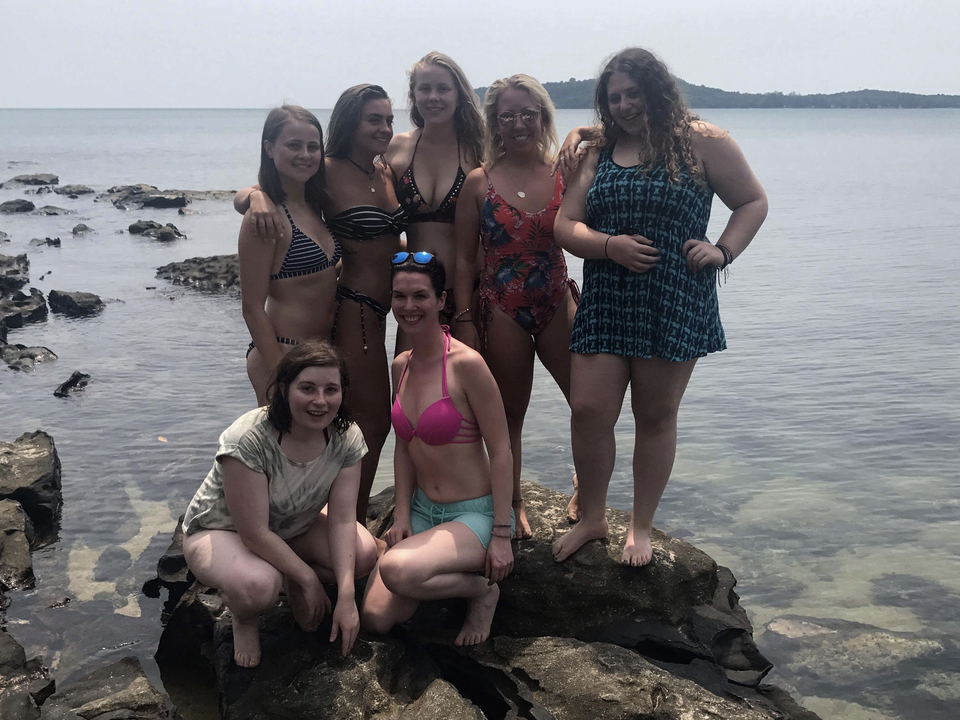 Group of friends posing on rocks by the water.