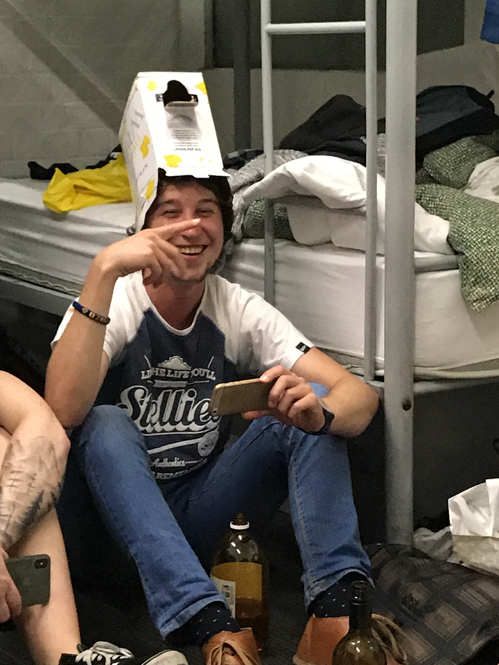 Person sitting on the floor smiling and holding a phone.