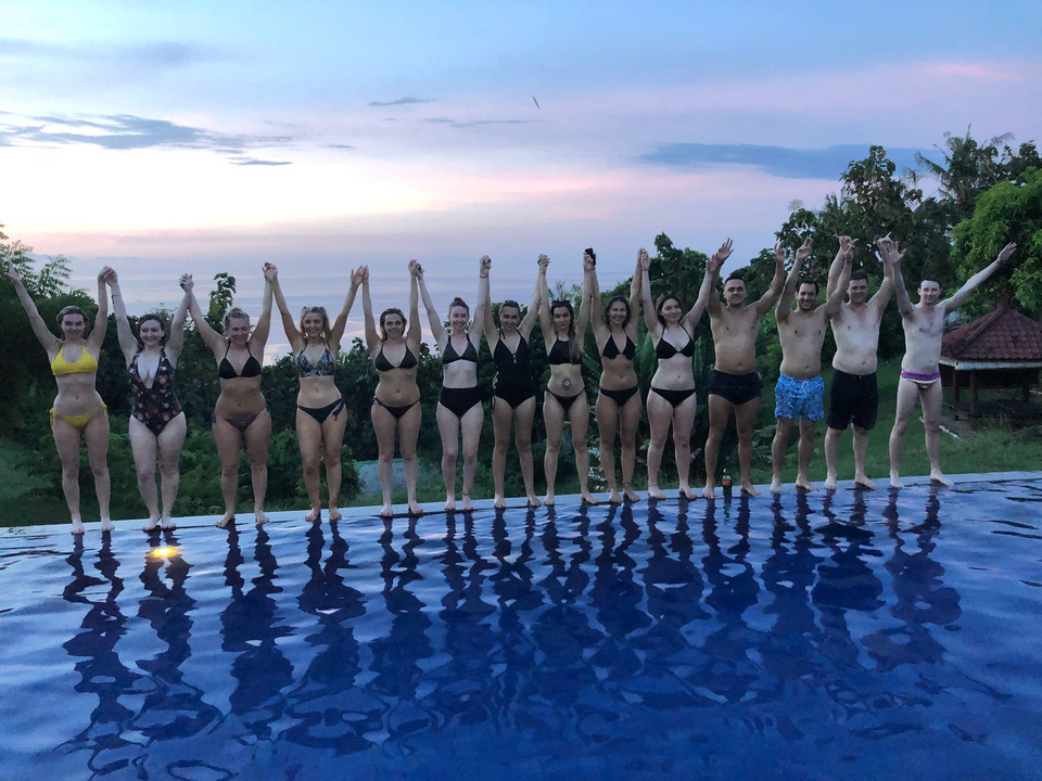 People holding hands along a poolside.